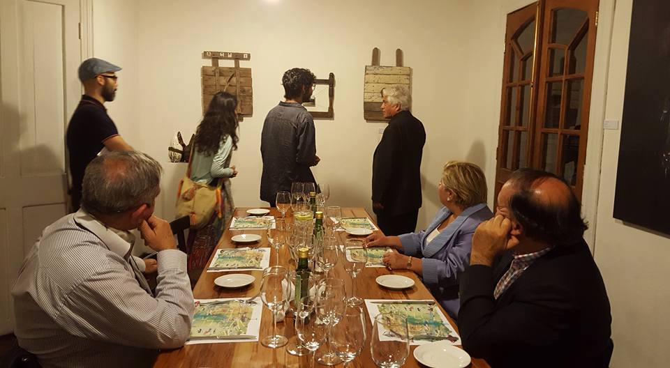 Personas sentadas al rededor de una mesa, mirando una obra de arte montada en la pared