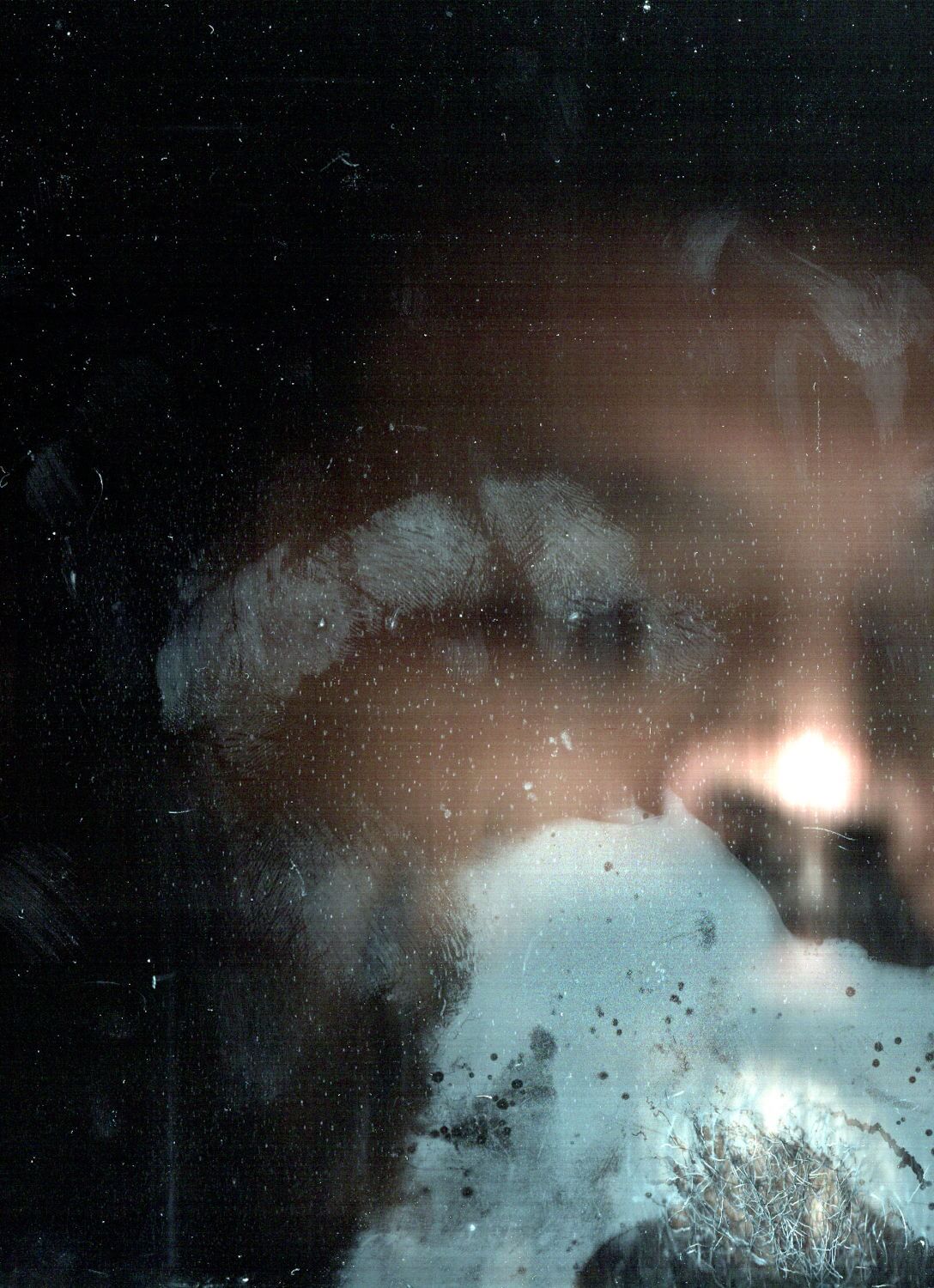 Rostro de hombre exhalando vapor sobre un vidrio, con fondo oscuro